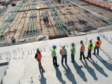 Photo prise en hauteur d'un groupe de personnes sur un chantier avec gilets et casques de sécurité